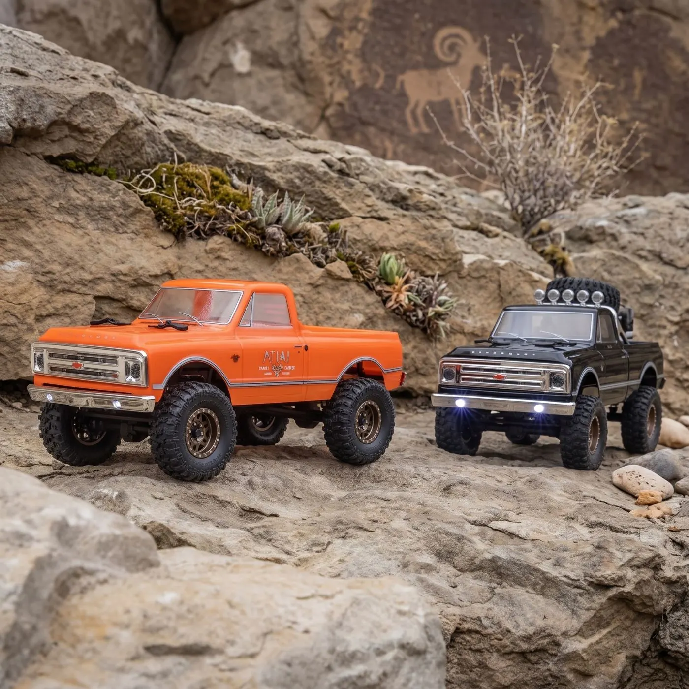 Two hobby-grade 1:24 scale RC crawler trucks, orange and black, climbing sandstone rock